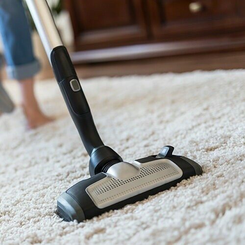 Woman using a vacuum cleaner while cleaning carpet | Custom Floor & Design